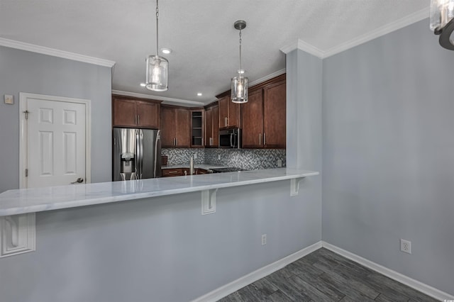 kitchen featuring stainless steel appliances, decorative light fixtures, a kitchen bar, and kitchen peninsula