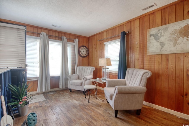 sitting room with hardwood / wood-style floors, a textured ceiling, and wood walls