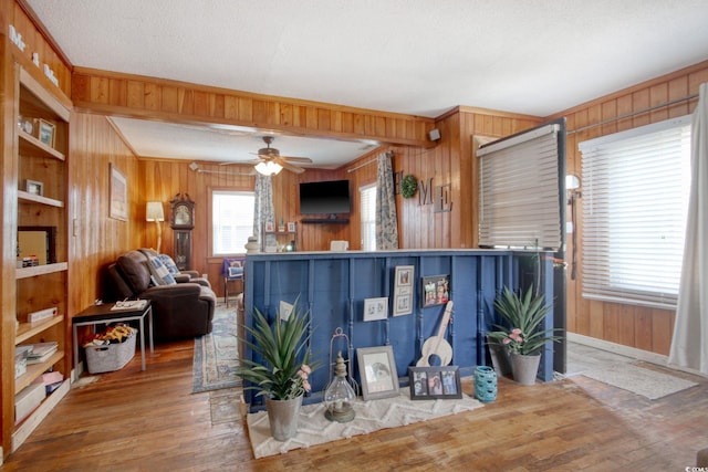 living room featuring crown molding, hardwood / wood-style flooring, a textured ceiling, and wood walls