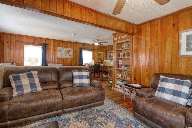 living room with hardwood / wood-style flooring, ceiling fan, a textured ceiling, and wooden walls