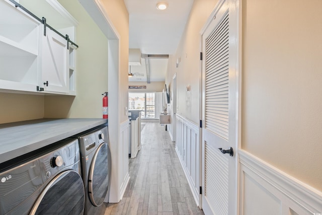 4609 Lightkeepers Way Unit 11J, Little River, SC 29566 - laundry area featuring washing machine and clothes dryer, a barn door, light wood-style floors, cabinet space, and wainscoting