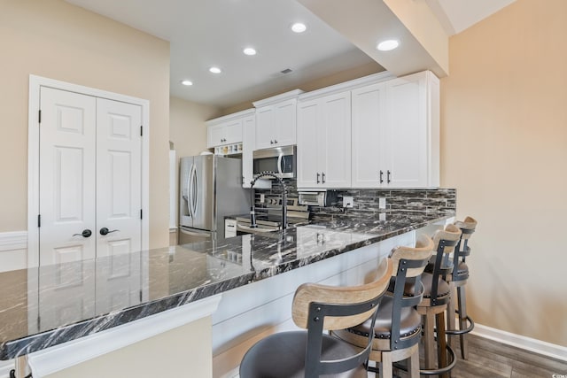 4609 Lightkeepers Way Unit 11J, Little River, SC 29566 - kitchen featuring dark stone countertops, recessed lighting, decorative backsplash, stainless steel appliances, and dark wood-style flooring