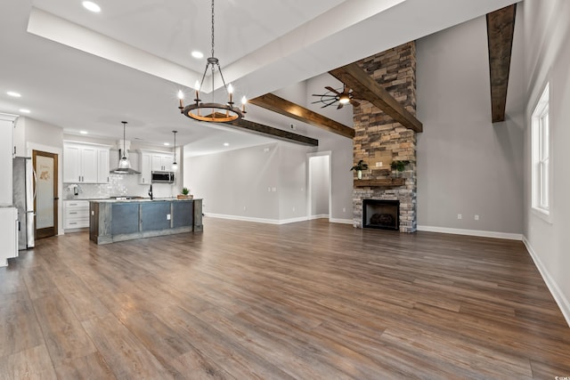 unfurnished living room featuring recessed lighting, baseboards, wood finished floors, and a stone fireplace