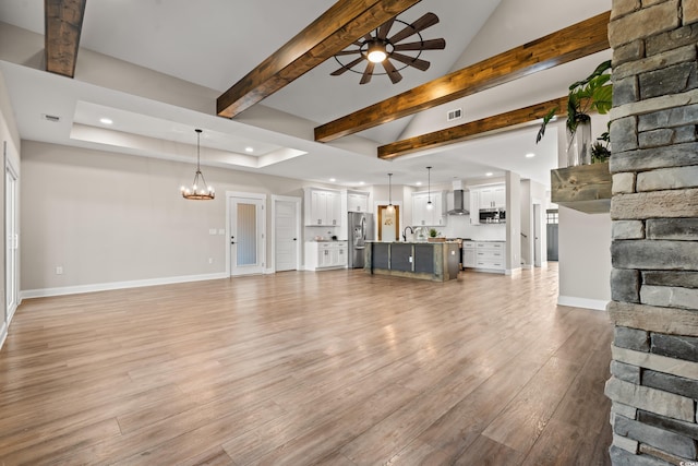 unfurnished living room featuring recessed lighting, ceiling fan with notable chandelier, visible vents, baseboards, and light wood-style floors