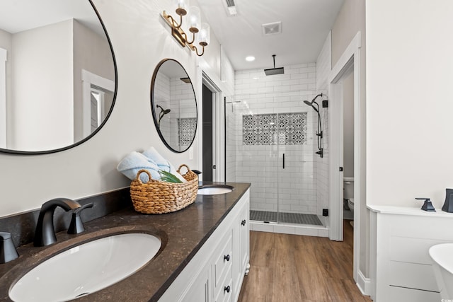 bathroom with wood finished floors, a stall shower, a sink, and visible vents