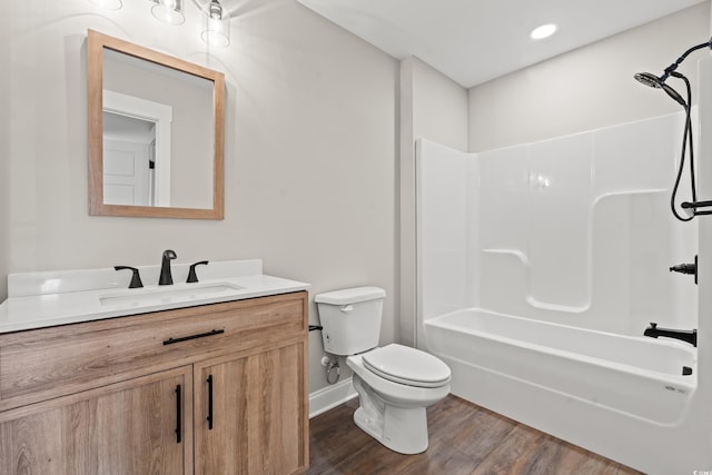 bathroom with bathtub / shower combination, toilet, wood finished floors, vanity, and baseboards