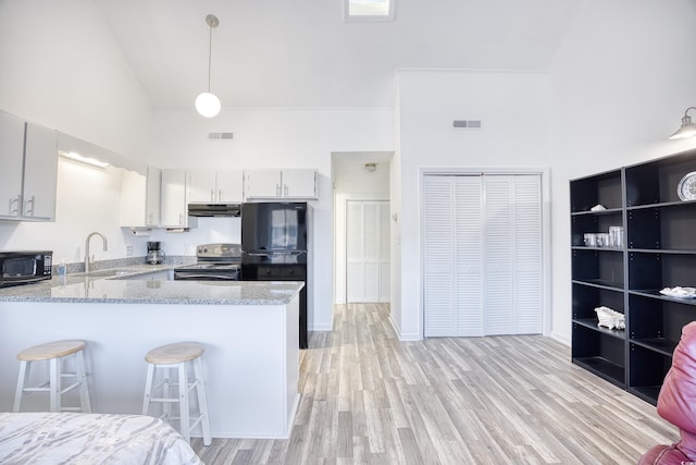 kitchen featuring black appliances, sink, a kitchen bar, hanging light fixtures, and kitchen peninsula