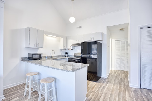 kitchen featuring decorative light fixtures, black appliances, sink, kitchen peninsula, and light stone countertops