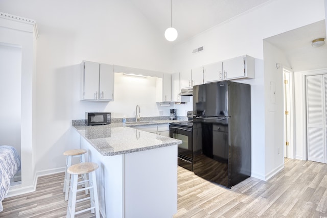 kitchen featuring pendant lighting, sink, black appliances, light hardwood / wood-style floors, and kitchen peninsula