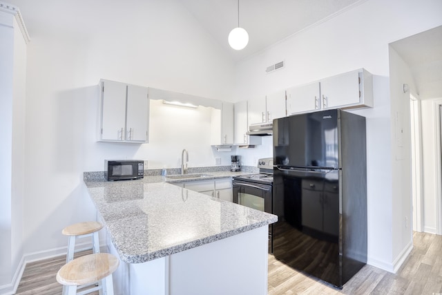 kitchen featuring pendant lighting, black appliances, sink, kitchen peninsula, and light hardwood / wood-style flooring