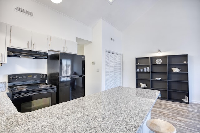 kitchen with light hardwood / wood-style flooring, white cabinetry, high vaulted ceiling, light stone counters, and black appliances