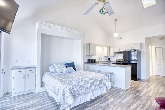 bedroom with black refrigerator, high vaulted ceiling, sink, ceiling fan, and light wood-type flooring