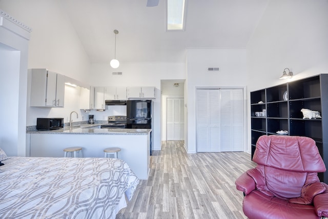 kitchen with pendant lighting, sink, light hardwood / wood-style flooring, black appliances, and kitchen peninsula