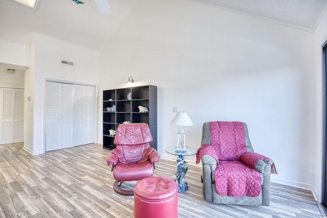 living area with ornamental molding, high vaulted ceiling, and light hardwood / wood-style floors