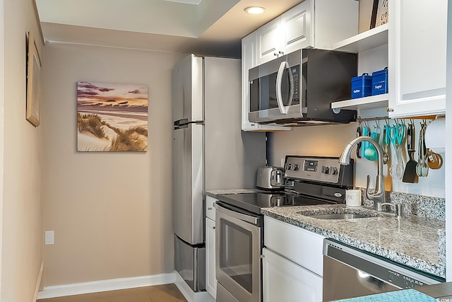 kitchen featuring white cabinetry, sink, light stone counters, and appliances with stainless steel finishes