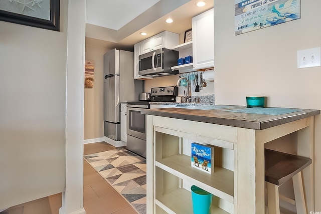 kitchen with stainless steel appliances, white cabinets, and wood counters