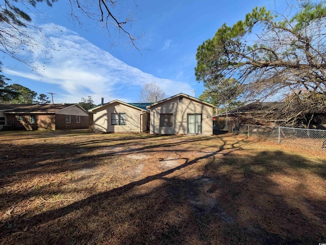 rear view of property featuring fence and a lawn