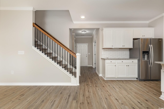 kitchen with stainless steel refrigerator with ice dispenser, crown molding, tasteful backsplash, light hardwood / wood-style floors, and white cabinets