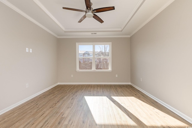 unfurnished room with ceiling fan, ornamental molding, a tray ceiling, and light hardwood / wood-style flooring