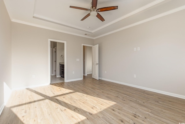 unfurnished room with ceiling fan, ornamental molding, a tray ceiling, and light hardwood / wood-style floors