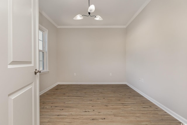 empty room featuring a notable chandelier, crown molding, and light hardwood / wood-style floors