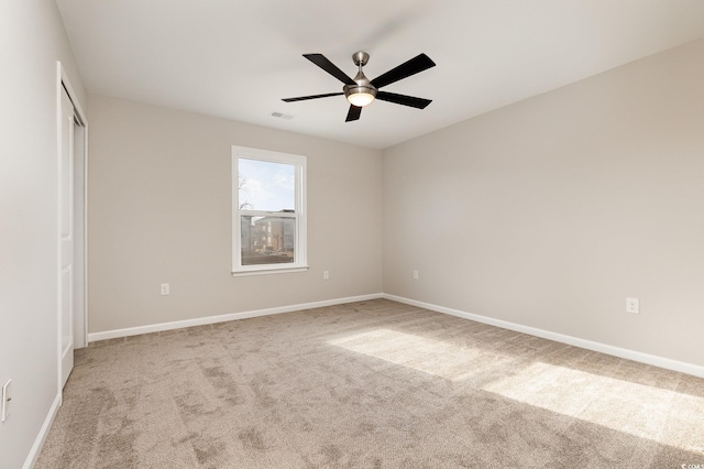 unfurnished room with light colored carpet and ceiling fan