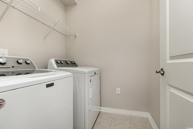 clothes washing area featuring washing machine and dryer and light tile patterned floors