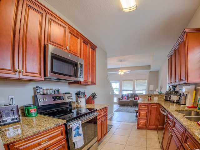 kitchen featuring ceiling fan, appliances with stainless steel finishes, light tile patterned floors, and light stone counters