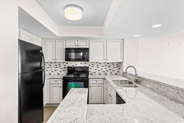 kitchen with light stone countertops, sink, kitchen peninsula, and black appliances