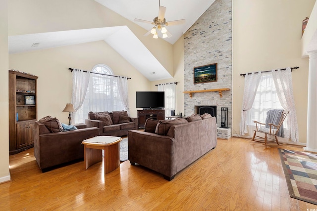 living room featuring ceiling fan, high vaulted ceiling, a large fireplace, and light hardwood / wood-style floors