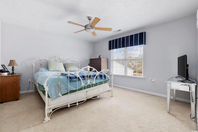 carpeted bedroom featuring ceiling fan and a textured ceiling