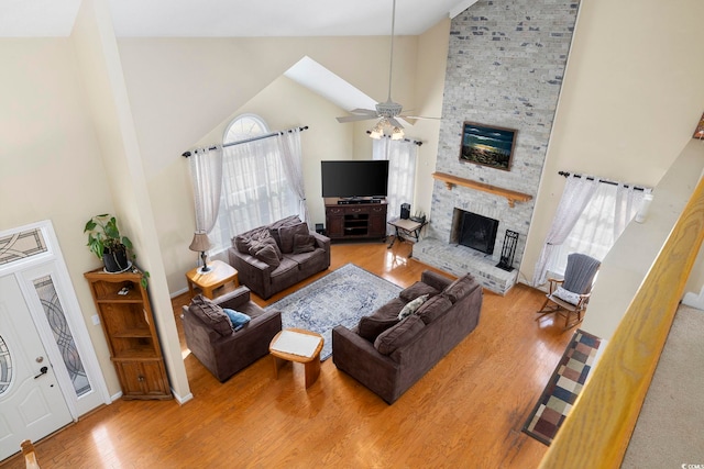 living room with ceiling fan, high vaulted ceiling, a fireplace, and light hardwood / wood-style floors