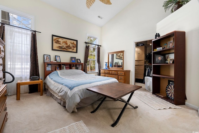 carpeted bedroom featuring a walk in closet, high vaulted ceiling, and a closet