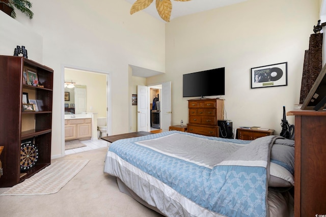 bedroom with a towering ceiling, ensuite bathroom, and light tile patterned floors