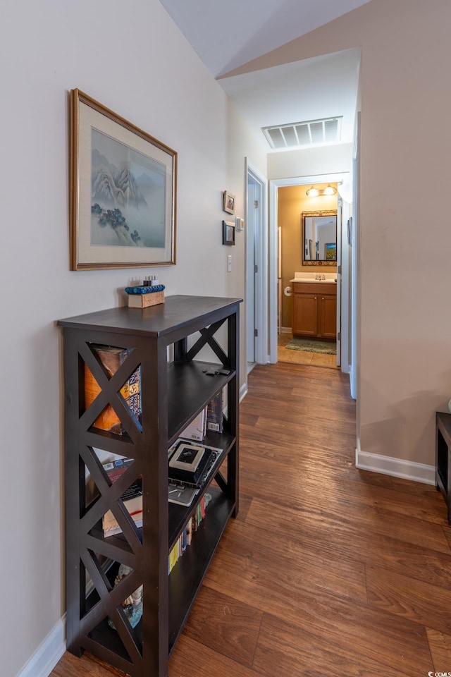 corridor with dark wood-style floors, visible vents, and baseboards