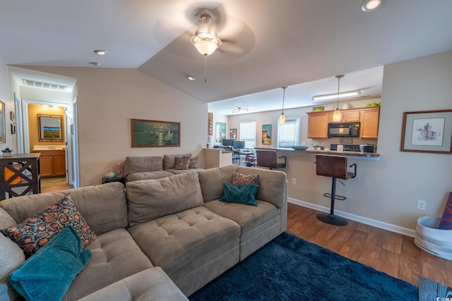 living area featuring lofted ceiling, ceiling fan, visible vents, baseboards, and dark wood finished floors