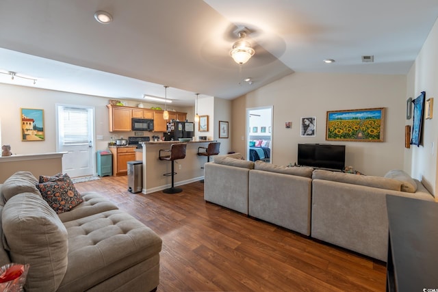 living area featuring dark wood-style floors, plenty of natural light, visible vents, and vaulted ceiling