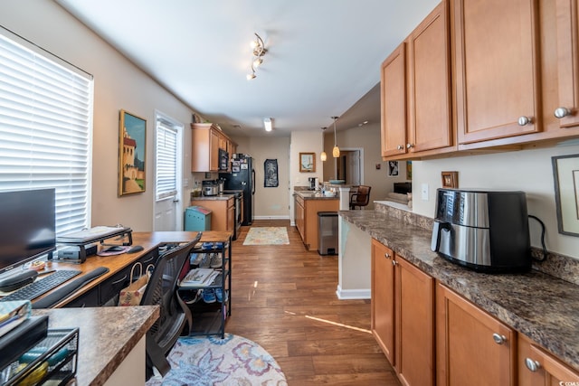 kitchen featuring dark wood-style floors, dark countertops, hanging light fixtures, black appliances, and baseboards