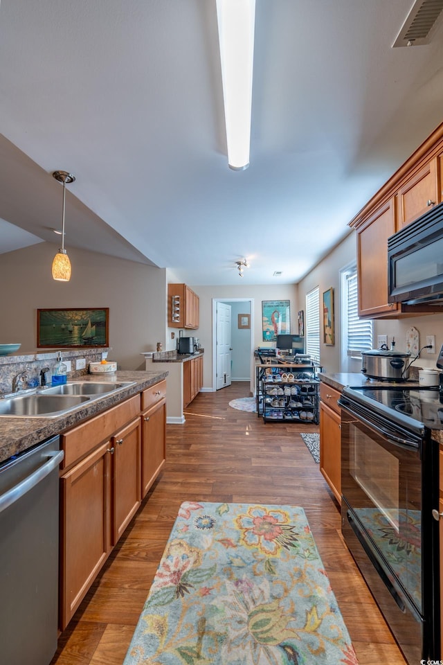 kitchen with visible vents, dark countertops, wood finished floors, hanging light fixtures, and black appliances