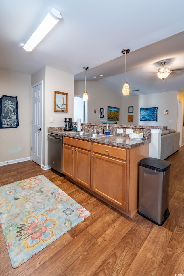 kitchen with hanging light fixtures, stainless steel dishwasher, brown cabinetry, light wood-style floors, and open floor plan