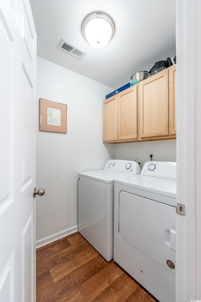 laundry area featuring dark wood-type flooring, visible vents, cabinet space, and washer and clothes dryer