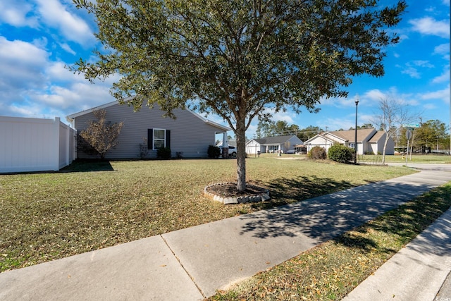 view of side of home featuring a yard, fence, and a residential view