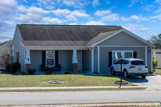 view of front of property featuring a shingled roof, a porch, concrete driveway, and a front yard