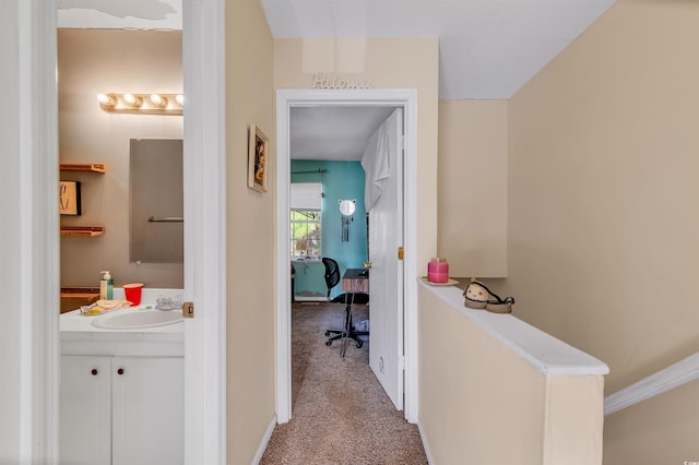 corridor with sink and light colored carpet