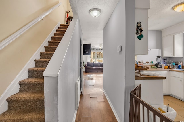 staircase featuring hardwood / wood-style flooring and a textured ceiling