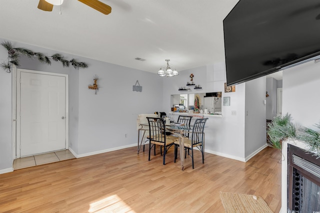 dining area featuring ceiling fan with notable chandelier and light wood-type flooring