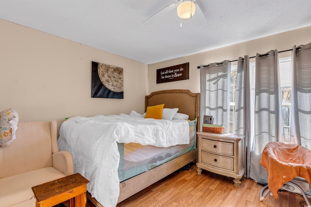 bedroom with a textured ceiling, ceiling fan, and light hardwood / wood-style flooring