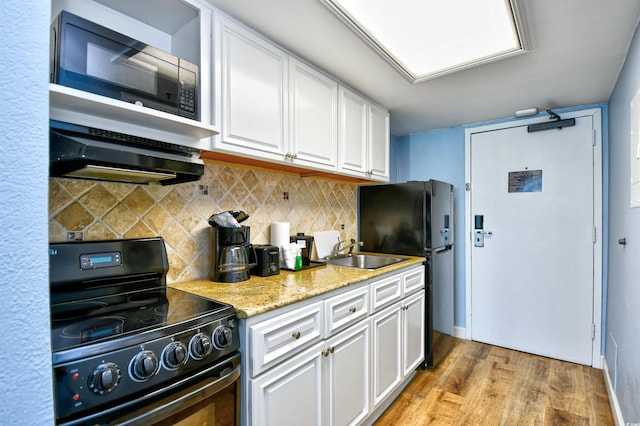 kitchen featuring tasteful backsplash, white cabinetry, sink, black appliances, and light wood-type flooring