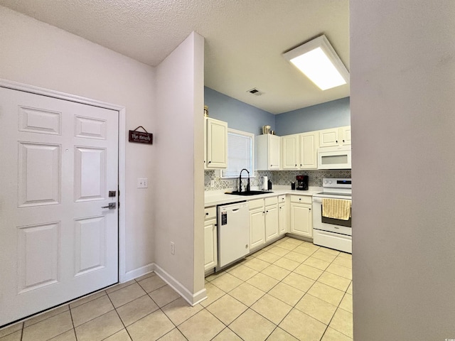 kitchen with sink, white appliances, light tile patterned floors, white cabinetry, and decorative backsplash