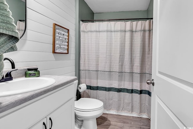 bathroom featuring vanity, hardwood / wood-style floors, toilet, and wood walls